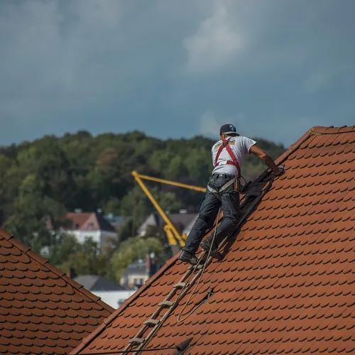 Trabalhador a reparar uma cobertura, em segurança com arnês
